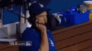 a man in a la hat is talking on a cell phone .