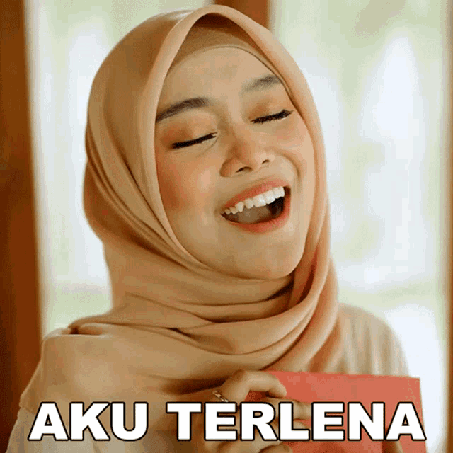 a woman wearing a hijab is holding a red envelope with aku terlena written on it