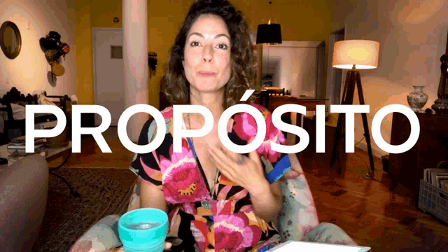 a woman sits in front of a sign that says " propósito "