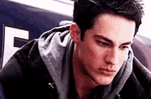 a young man wearing a hoodie and a black jacket is looking down .