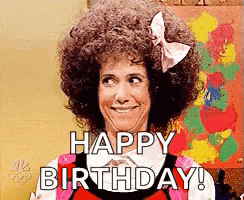 a woman with an afro and a bow in her hair is smiling and says happy birthday .