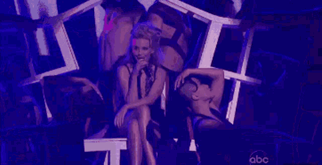 a woman is singing into a microphone on stage in front of a purple background .