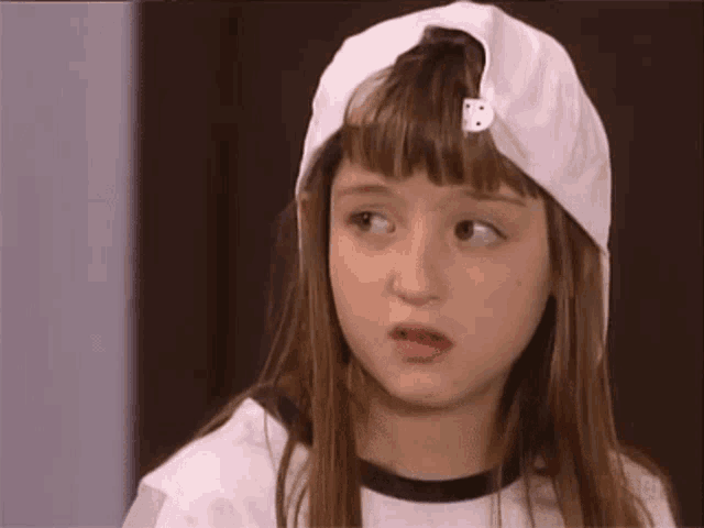 a young girl wearing a white hat and a white shirt .