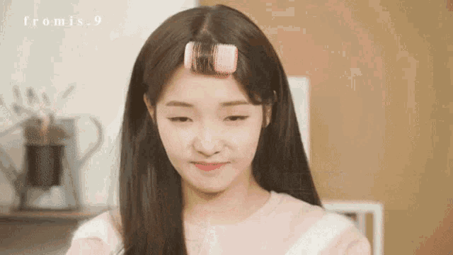 a woman with curlers in her hair is smiling and looking down