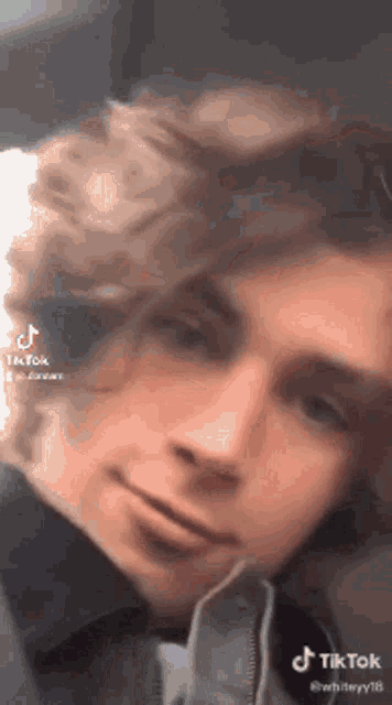 a close up of a young man 's face with a tiktok watermark on it .