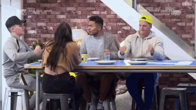 a group of people are sitting at a table with a brick wall behind them and the words new this week on the bottom