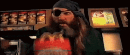a man in a pirate costume is eating a mcdonald 's burger