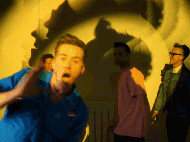 a group of men are standing in front of a wall with a shadow of a woman on it