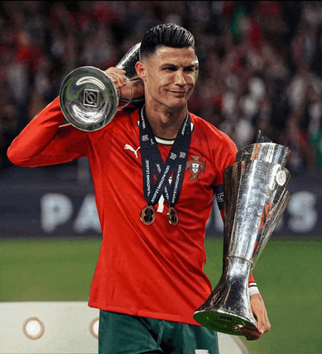 a soccer player holding a trophy with a medal around his neck that says ' uefa nations league '