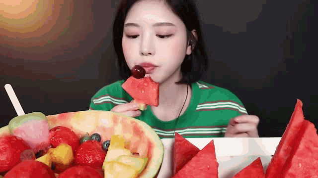 a woman is eating a slice of watermelon with a cherry on top of it .
