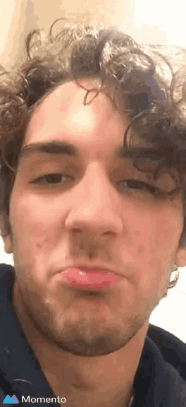 a young man with curly hair is making a funny face with a momento icon next to him