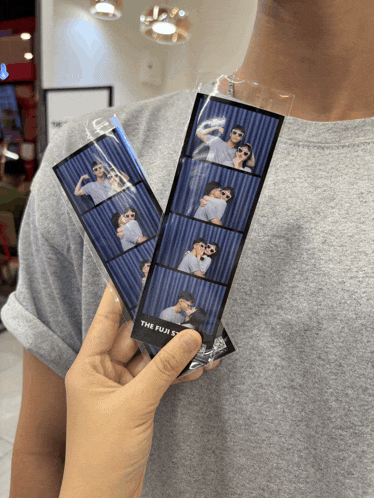 a person is holding two photo strips that say the fuji 5