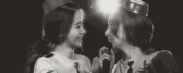 a couple of women standing next to each other holding microphones .
