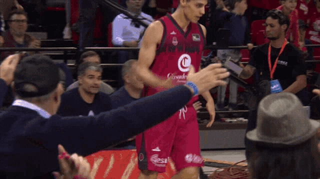 a basketball player wearing a jersey with the letter c on it is being greeted by a fan