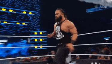 a man with a beard is walking out of a wrestling ring with a microphone in his hand .