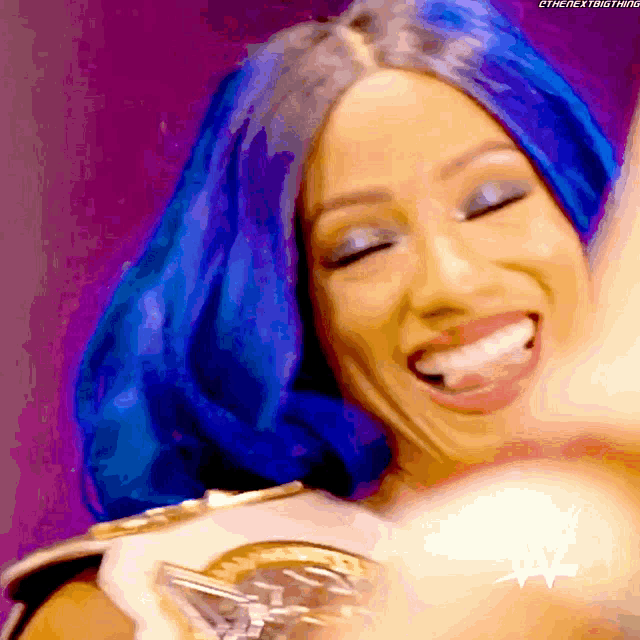 a woman with blue hair is smiling and wearing a wwe championship belt .