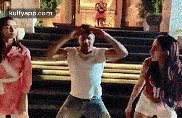 a man and two women are dancing together on a set of stairs .