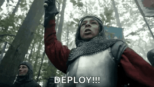 a man in a knight 's armor is standing in the woods holding a sword and shouting .