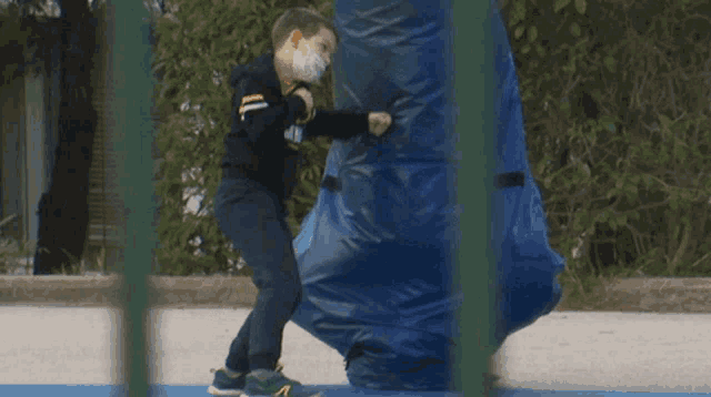 a boy wearing a mask is playing with a blue tarp