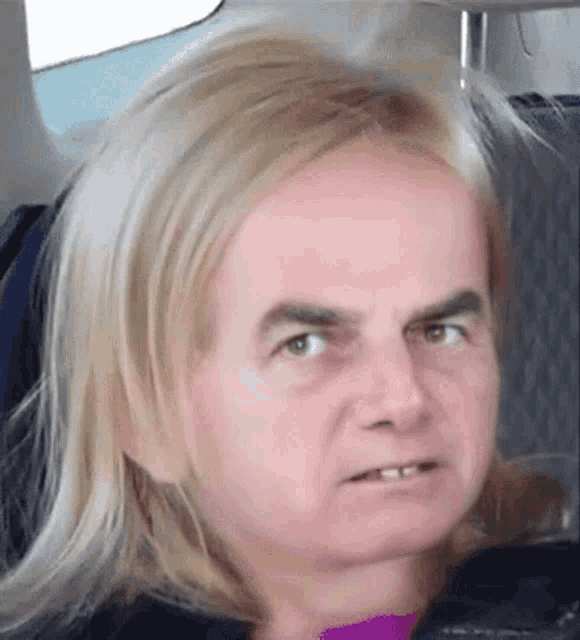 a man with long blonde hair and a beard looks at the camera