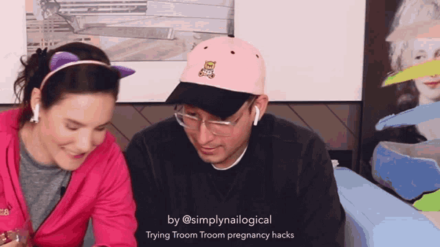 a man wearing a pink hat with a teddy bear on it is sitting next to a woman