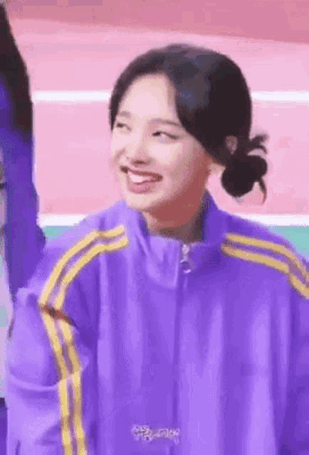 a young woman wearing a purple jacket with yellow stripes is smiling .