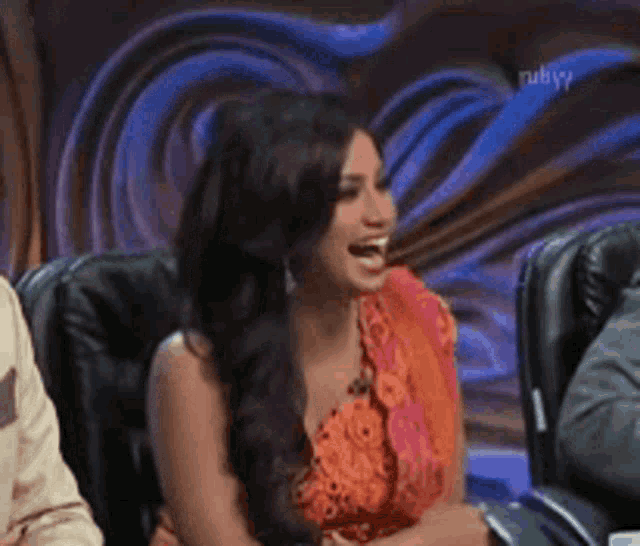 a woman is laughing while sitting in a chair with ruby on the bottom left