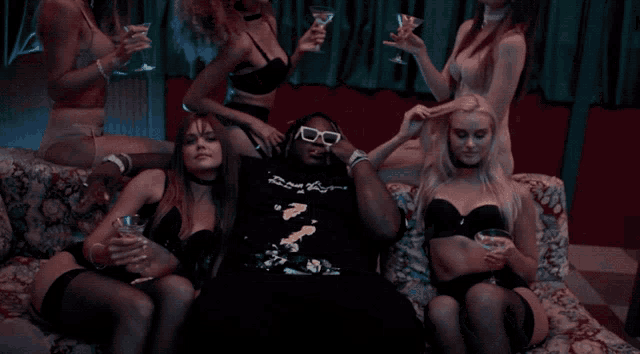 a man is surrounded by a group of women holding drinks