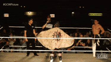 two wrestlers in a ring with a sign that says merchandise