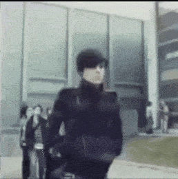 a blurry picture of a man wearing sunglasses and a hat walking in front of a building .