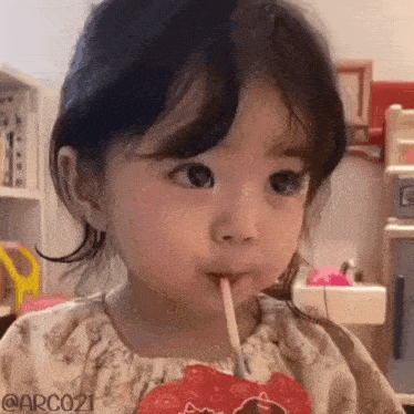 a little girl is drinking from a straw from a juice box .
