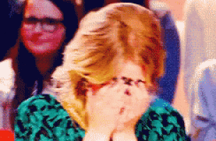 a woman covering her face with her hands in a crowd of people