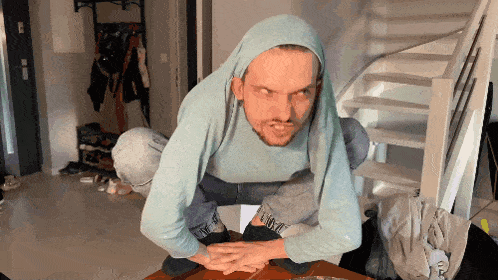 a man wearing a blue sweater with the word nike on it is squatting on a table