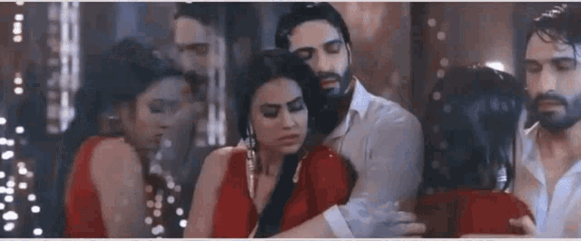 a man and a woman are hugging each other in a room . the woman is wearing a red dress .