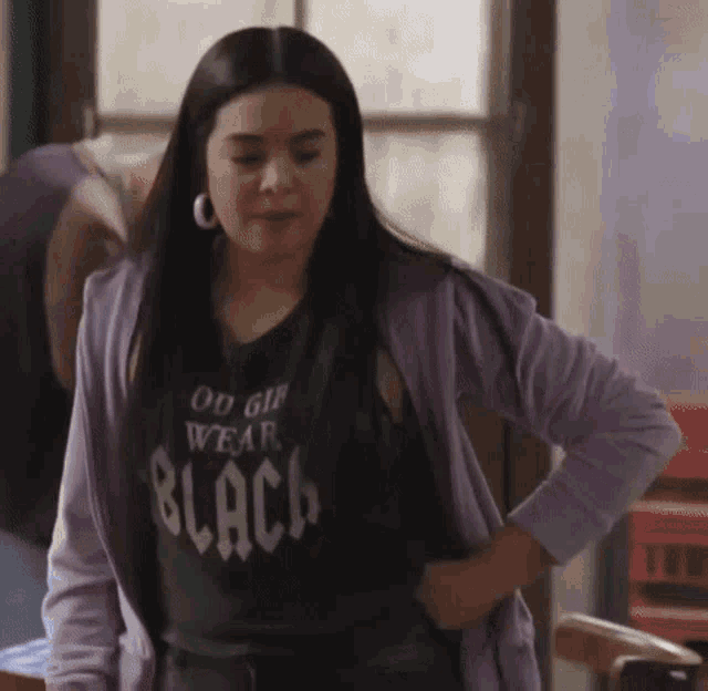 a woman wearing a purple jacket and a black t-shirt that says " ou girl wear black "