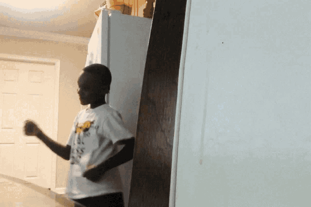a boy wearing a shirt that says ' i love you ' on it stands in front of a refrigerator