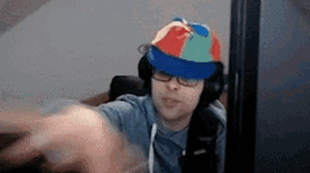 a man wearing a hat and headphones is sitting in front of a computer screen .