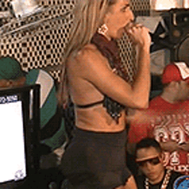 a woman in a bikini is singing into a microphone in front of a crowd .