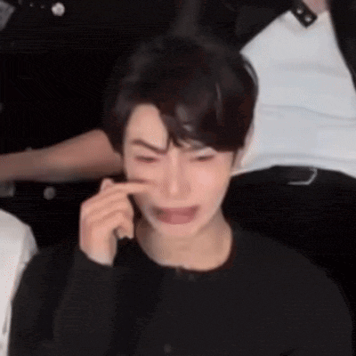 a man is crying while talking on a cell phone in a crowded room .