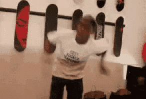 a man is dancing in front of a wall with skateboards on it .