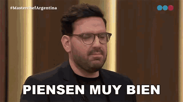 a man with glasses says " piensen muy bien " on a television screen