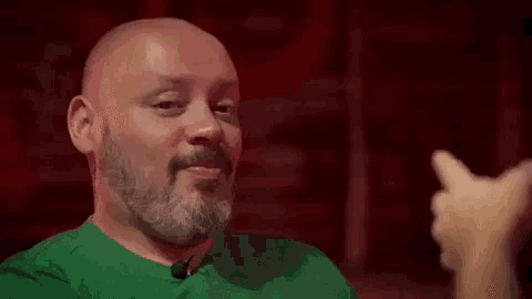 a bald man with a beard is giving a thumbs up .