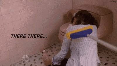 a woman is cleaning the floor in a bathroom with a mop and a toilet .