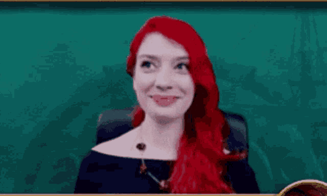 a woman with red hair is sitting in front of a green wall .