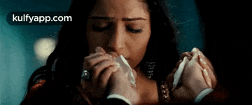 a woman is holding a man 's hand in front of her face .