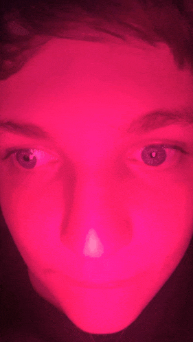 a close up of a person 's face with a pink light shining on it