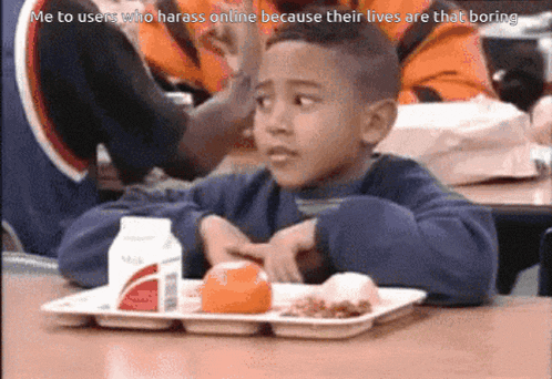 a young boy sitting at a table with a tray of food and a caption that says me to users who harass online