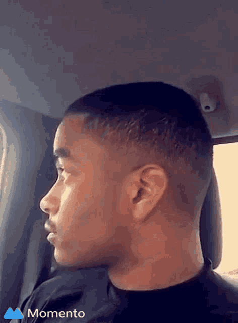 a young man is sitting in the back seat of a car and the word momento is on the bottom right corner
