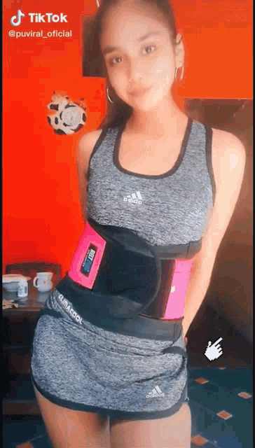 a girl is wearing a gray tank top and shorts with an adidas logo