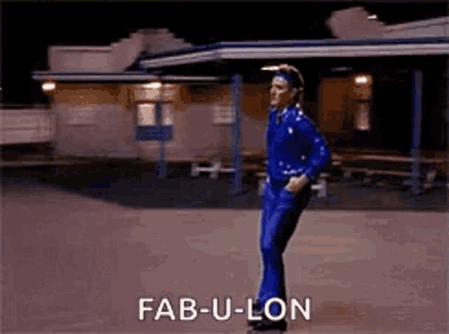 a man in a blue suit is dancing in front of a building with the words fab-u-lon written on it .